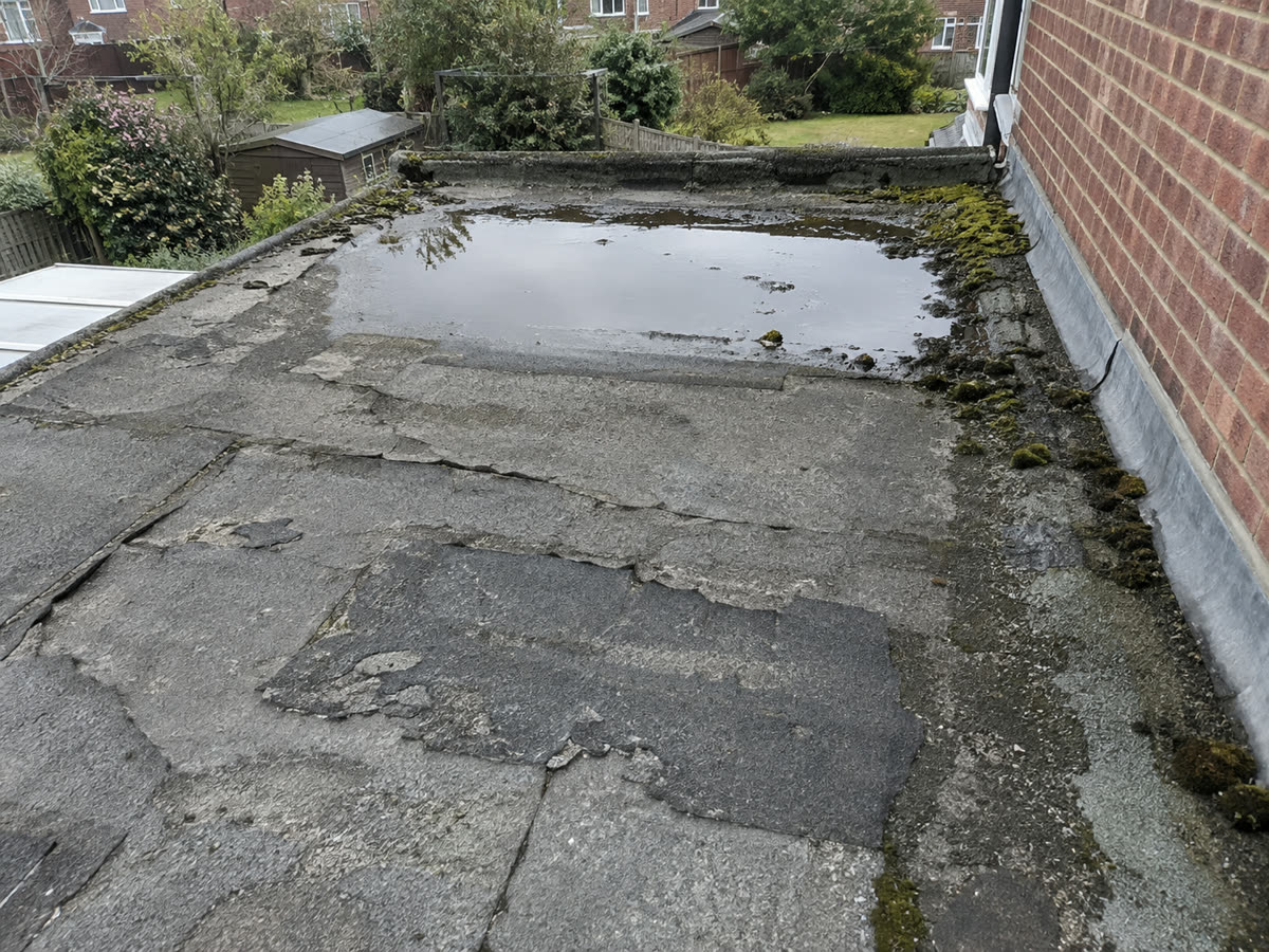 Before: a cracked felt flat roof holding water